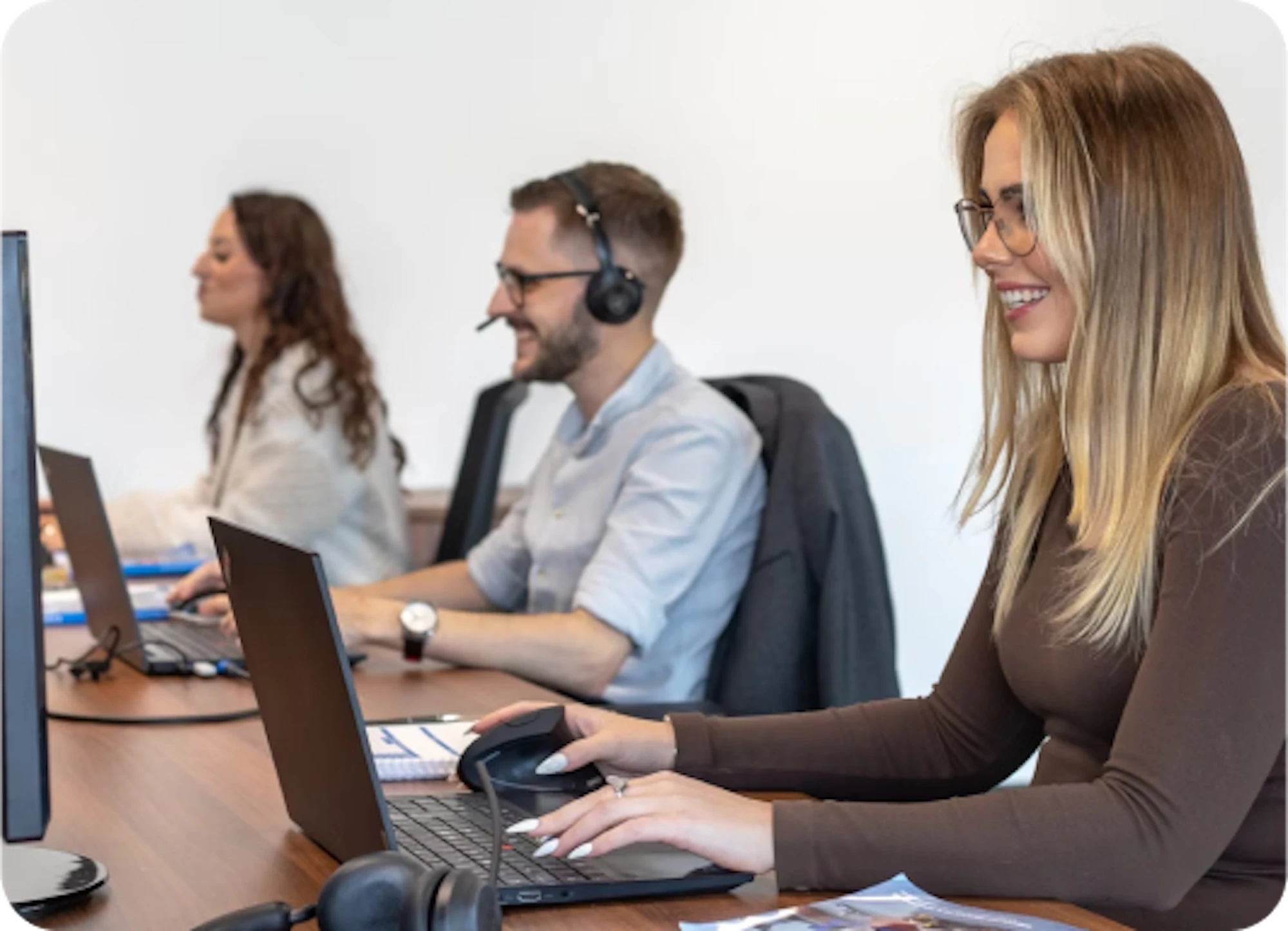 three people as customer services reps with headsets typing on laptop