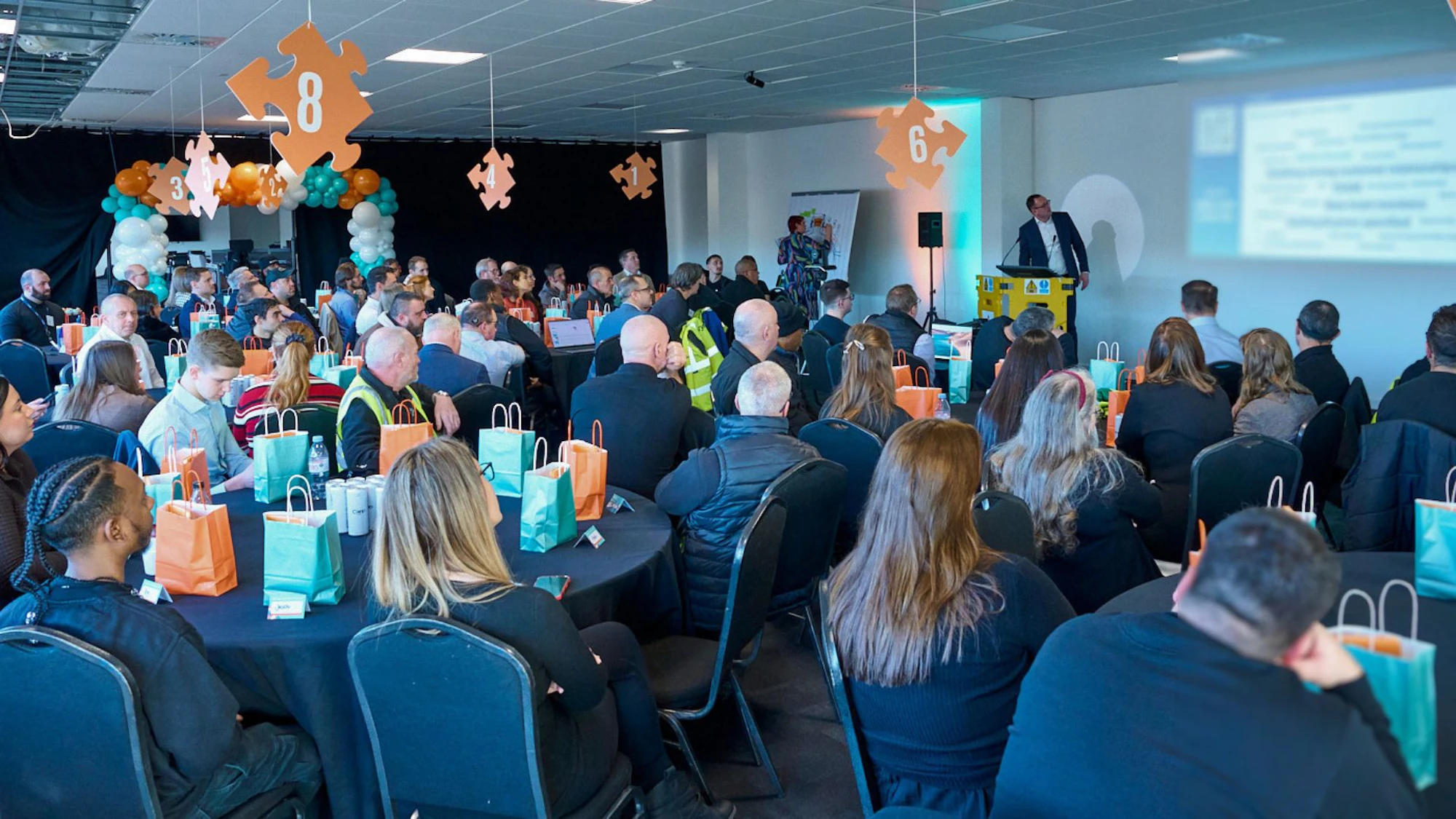 big group of brymec employees at event looking at manager presenting from podium