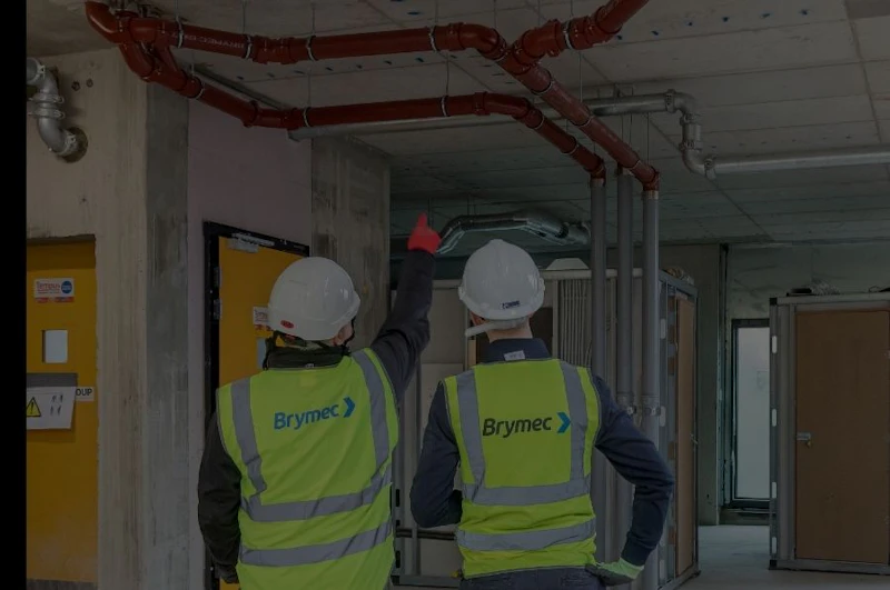 two brymec employees in high vis observing brymec cast iron installed on site